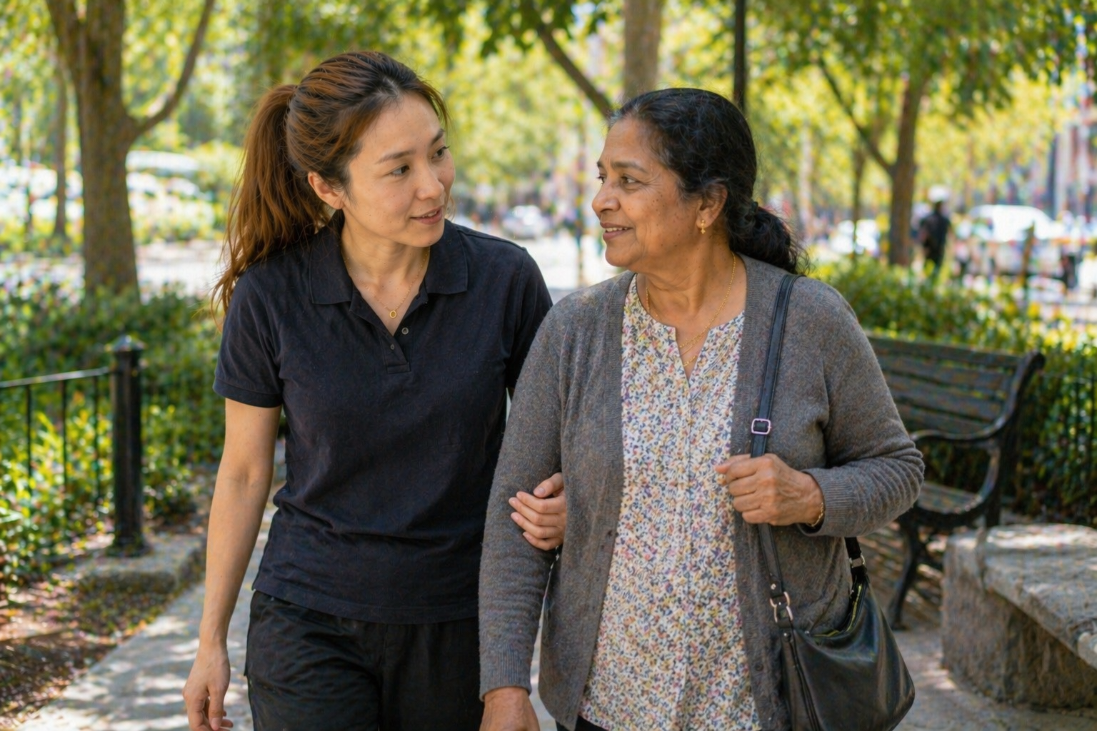 Support worker walking arm in arm with elderly Indian woman in a park — companionship and social support Melbourne